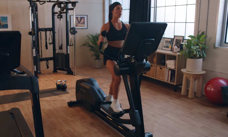 Žena koristi eliptik mašinu u svojoj sobi